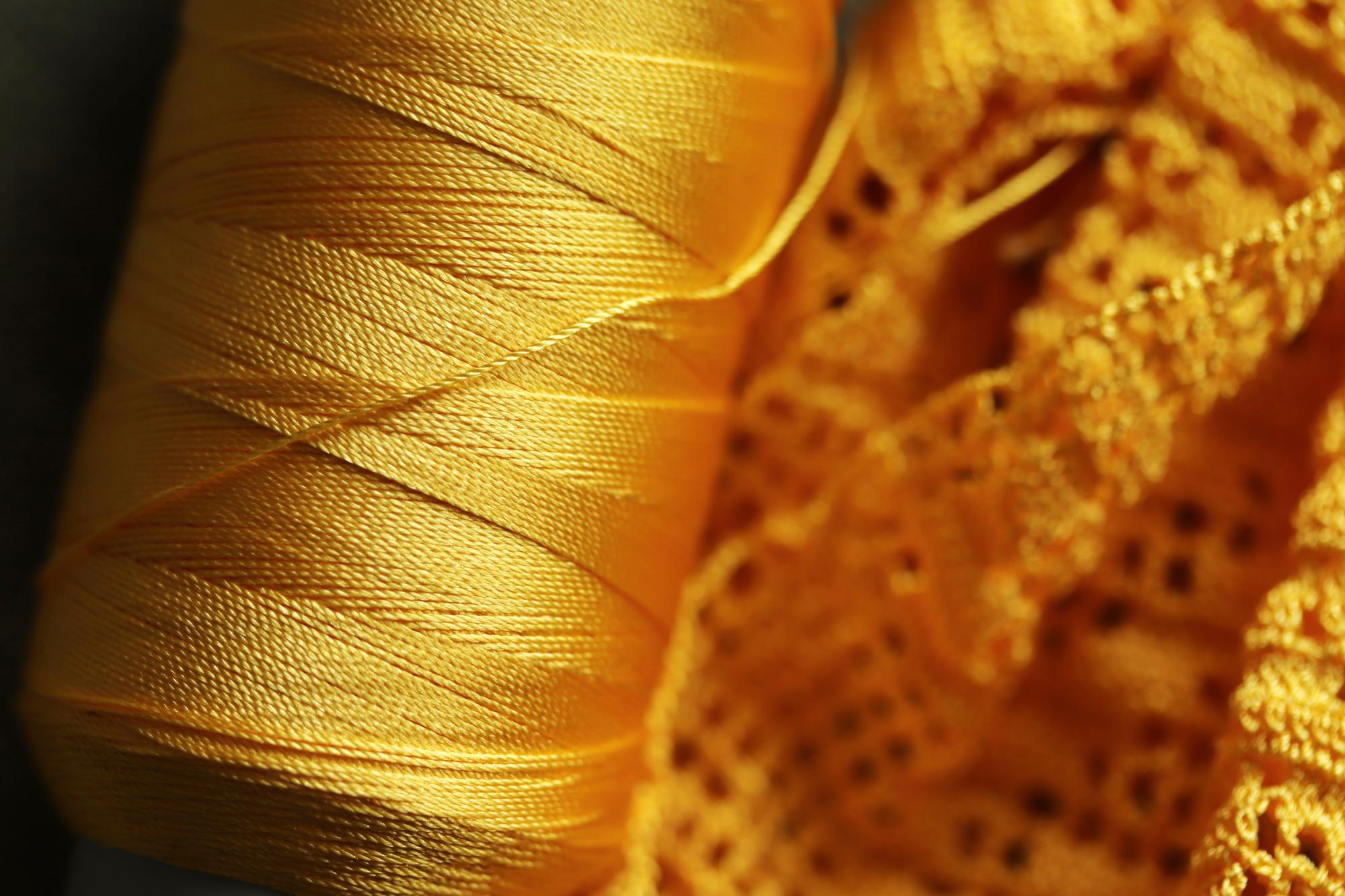 Close-up of bespoke gold thread embroidery on dark fabric